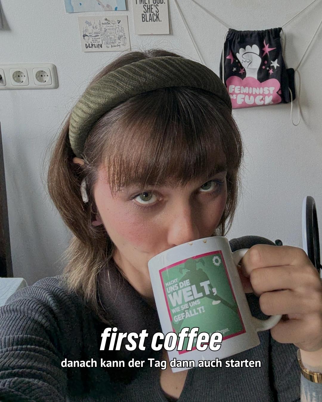Nyke Slawik trägt ein olivgrünes Stirnband und hält eine weiße Tasse mit grünem und rotem Rand. Text: "first coffee - danach kann der Tag dann auch starten"